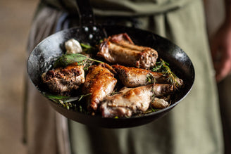 A pan of cooked, crispy, wild rabbit meat with herbs.