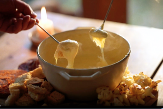 A mixed cheese fondue with an array of accompaniments to dip.