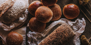 Artisan bread including loaves and buns, made with a 65-year-old starter, slow fermentation, and heritage grains.
