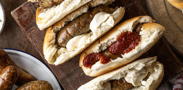 Grilled Natural Pork Sausages Encased in Soft Hotdog Buns From Hobbs Bakery and Smothered in Ketchup and Mayonnaise 
