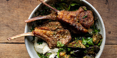 A meal of cooked Grass Fed Lamb Chops with vegetables and herbs.