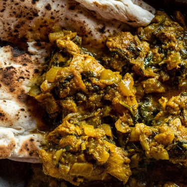 A bowl of Bini's Jammu Chicken Curry Healthy Ready Meal with naan and white rice.