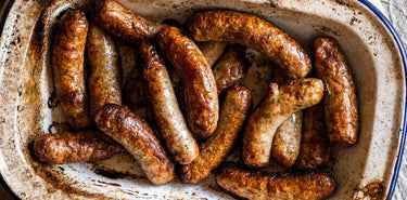 A tray of cooked, natural sausages.
