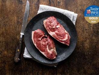 A pair of raw grass fed lamb rump steaks on a plate.
