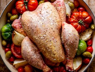 A whole, cooked. 100% pastured properly free range chicken on a bed of tomatoes, garlic, onion, and seasonings.