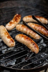 Natural, free range, sage and onion turkey sausages cooking on a barbecue.