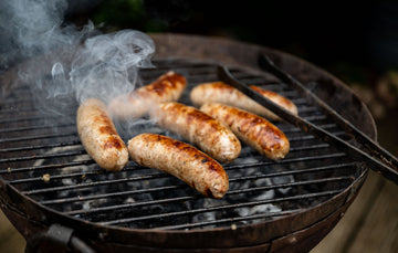 Natural, free range, sage and onion turkey sausages cooking on a barbecue.
