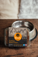 Benyfit Turkey Meat Feast pet food packaging on a wooden surface with a metal bowl in the background.