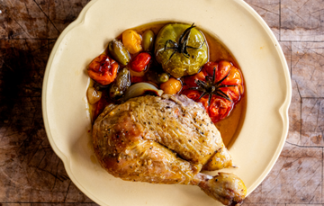 A cooked leg of a 100% pastured properly free range chicken with tomatoes, garlic, onions, and cooking juices.