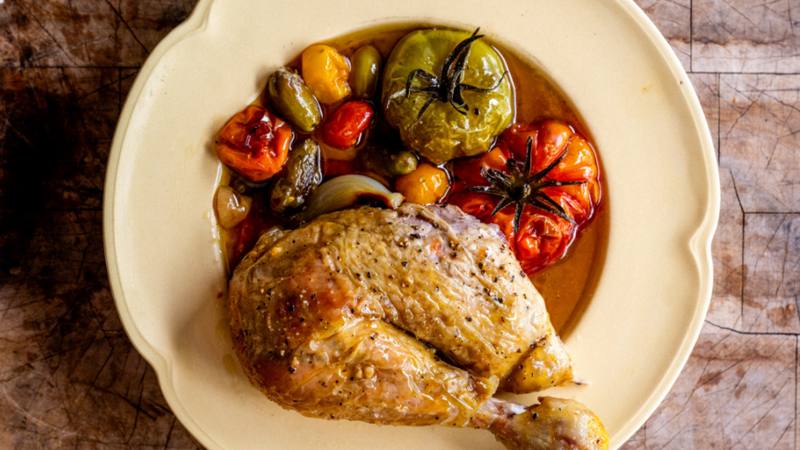 A cooked leg of a 100% pastured properly free range chicken with tomatoes, garlic, onions, and cooking juices.