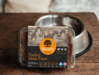 Benyfit Turkey Meat Feast pet food packaging on a wooden surface with a metal bowl in the background.