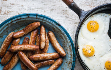 cooked native breed pork breakfast sausages with fried eggs