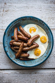 cooked native breed pork breakfast sausages with fried eggs