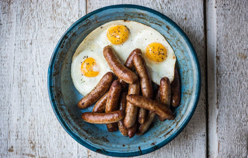 cooked native breed pork breakfast sausages with fried eggs