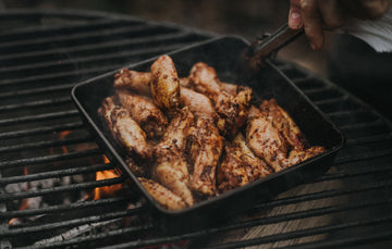 A pan of marinated properly free range chicken wings cooking over a barbecue.