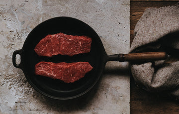 A pair of grass fed beef entrecote steaks in a frying pan.