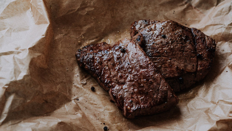 Two cooked grass fed beef everyday steaks with seasoning