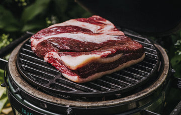 A piece of grass fed flat beef brisket cooking on a barbecue.