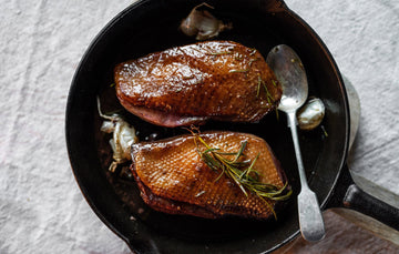 Cooked properly free range goose breasts with herbs and garlic in a pan.