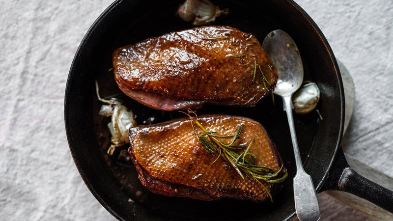 Cooked properly free range goose breasts with herbs and garlic in a pan.