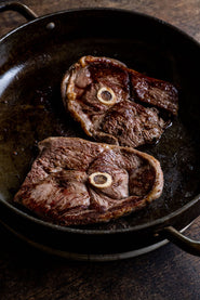 Grass fed lamb leg steaks cooking in a pan.