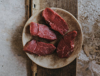 A plate of raw, grass fed lamb steaks.