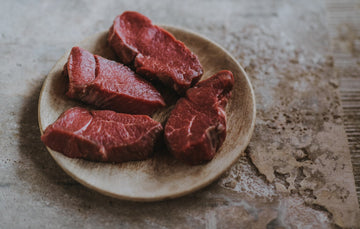 A plate of raw, grass fed lamb steaks.