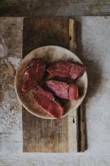 A plate of raw, grass fed lamb steaks.