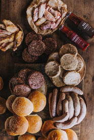 The contents of a large pipers farm bbq meat box including grass fed, properly free range meats, handmade sauces, and artisan buns.