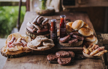 The contents of a large pipers farm bbq meat box including grass fed, properly free range meats, handmade sauces, and artisan buns.