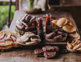 The contents of a large pipers farm bbq meat box including grass fed, properly free range meats, handmade sauces, and artisan buns.