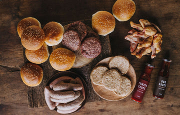 The contents of a Pipers Farm medium BBQ meat box including grass fed meats, handmade sauces, and artisan buns.