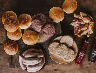 The contents of a Pipers Farm medium BBQ meat box including grass fed meats, handmade sauces, and artisan buns.