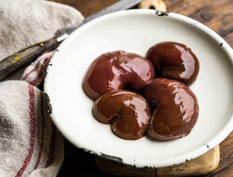 A plate showcasing four raw Native Breed Pig's kidneys