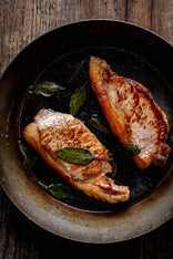 Native breed pork loin steaks cooking in a pan with herbs