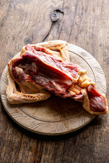 Raw duck carcass with wings on chopping board. 