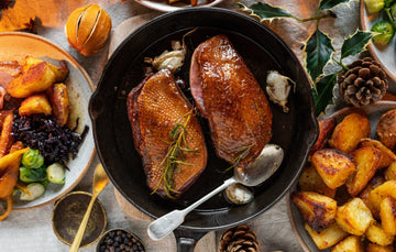 A roast dinner spread with potatoes, goose breasts, and vegetables.