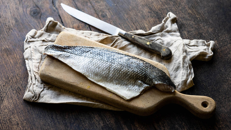 A British wild sea bass fillet on a chopping board.