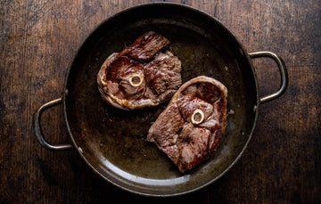 Grass fed lamb leg steaks cooking in a pan.