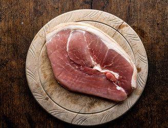 A native breed unsmoked gammon pork steaks cooking in a pan with mushrooms and eggs on a barbecue.