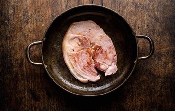A cooked native breed smoked gammon pork steak in a pan.