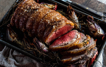 A cooked and sliced Grass Fed Beef Sirloin with onions and thyme.