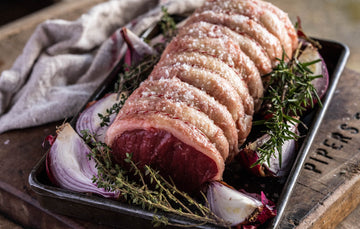 A raw and ready to cook Grass Fed Beef Sirloin with red onions and thyme.
