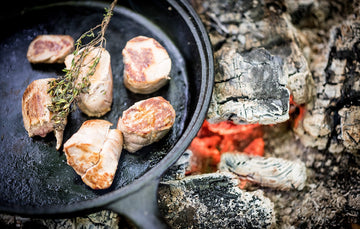 Native breed pork tenderloin cooking in a pan with fresh thyme