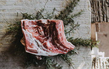 raw grass fed Lamb Shoulder on a bed of rosemary