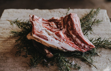 raw grass fed lamb shoulder on a bed of rosemary