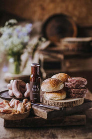 The contents of a Pipers Farm small BBQ meat box including grass fed meats, handmade sauce, and artisan buns.
