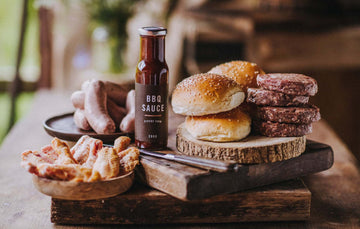 The contents of a Pipers Farm small BBQ meat box including grass fed meats, handmade sauce, and artisan buns.