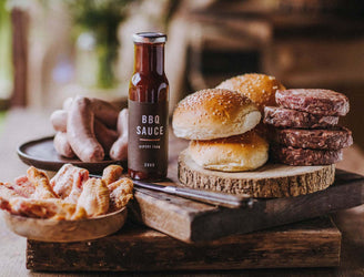The contents of a Pipers Farm small BBQ meat box including grass fed meats, handmade sauce, and artisan buns.