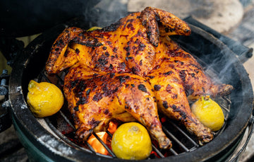 A whole, properly free range spatchcock chicken cooking on a barbecue with lemons